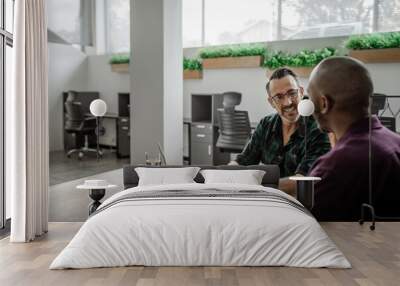 To diverse businessmen working on a laptop at an office table Wall mural