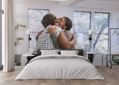 Two female black african freelancers embraced in a friendly hug in a modern co-working space Wall mural