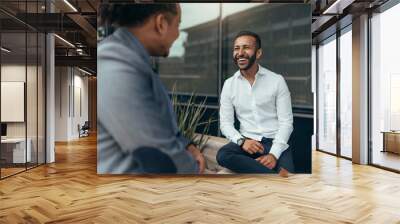 Two trendy businessmen talking and laughing casually outside Wall mural