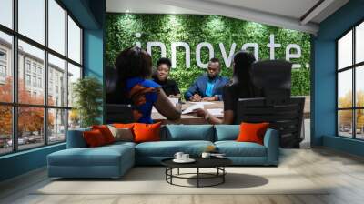 Young African businesswoman talking with colleagues during a boardroom meeting Wall mural