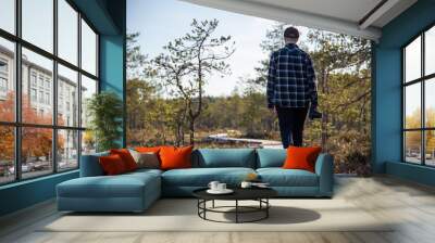 female person walking on duckboards in wetlands with a camera Wall mural