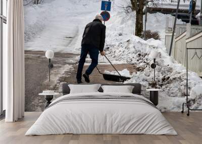 Man cleaning up the snow from the streets with a an equipment on a snowy day Wall mural