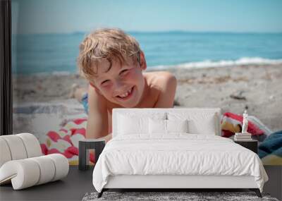 A happy boy smiling on a colorful towel at the beach in summer Wall mural