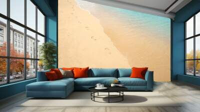 Footprints on sandy beach. Steps of human feet on clear gold sand with water sea line texture. Summer concept Wall mural