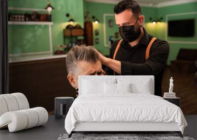 a barber combs an adult male with hand and comb, wears masks pandemic prevention coronavirus Wall mural