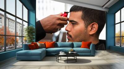 African-American barber's hand uses razor and haircut on Hispanic Latino man with goatee in a barbershop Wall mural