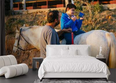 Disabled child doing mobility exercise during an equine therapy session Wall mural