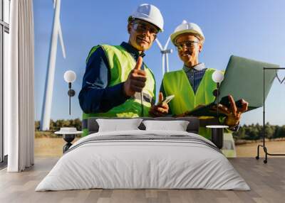 Engineer team looking at camera and smiling while working in the wind farm. Wall mural