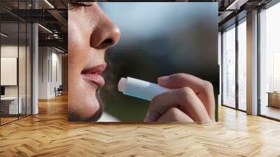 Close-up of beautiful young woman using lip balm to moisture lips. Wall mural