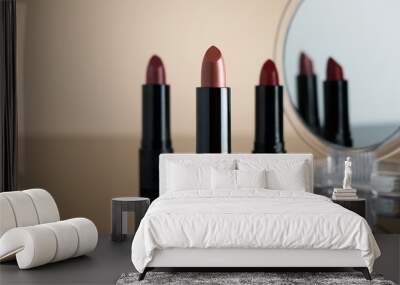 Set of lipsticks on cream reflective surface, two of them reflecting on a cosmetic mirror. Wall mural