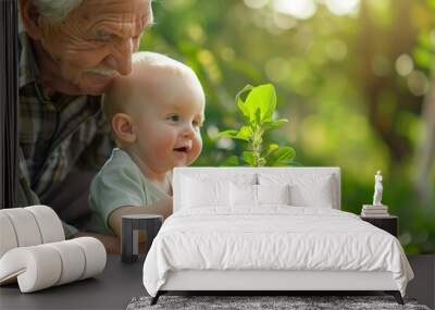 A Senior man and baby holding young plant in hands Wall mural