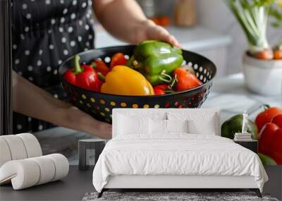 Woman taking bell pepper from black colander Wall mural