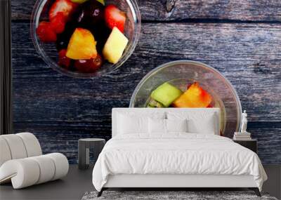 Top view of fresh sliced fruits in plastic cups on wooden background Wall mural