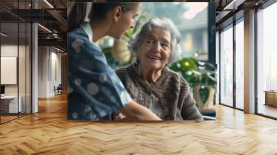 A woman in a blue shirt is sitting next to an older woman who is smiling Wall mural