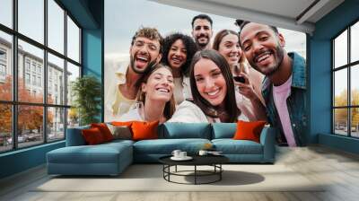 Big group of young adult happy friends smiling taking a selfie portrait and looking at camera with friendly expression. A lot of cheerful multiracial people celebrating and laughing. Buddies bonding Wall mural