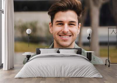 Caucasian happy male in university campus. Portrait of teenage male student standing in a college Wall mural