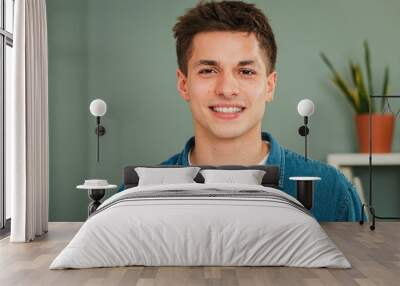 Close up individual portrait of one young adult caucasian guy smiling and looking at camera with friendly expression. Headshot of a real teenage man student with white teeth staring front at home Wall mural