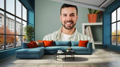 Close up portrait of one handsome guy with perfect white teeth smiling at home. Front view of young confident man with friendly and positive expression. Happy adult male laughing and looking at camera Wall mural