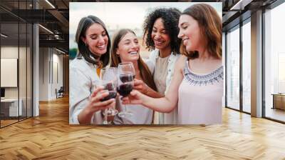 Group of happy young women friends having fun toasting wine glasses on a rooftop party, drinking and laughing together. Four cheerful girls smiling an clinking with drinks on a social reunion at bar Wall mural