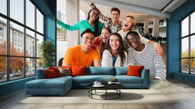 Group of young teenage students siting at library, using a laptop and looking at camera. Happy classmates studying and doing homeworks at high school. Multiracial academy people portrait. Schoolboys Wall mural