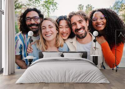 Portrait of a group of friends laughing together and looking at camera. Five young multiracial cherful people smiling and having fun. Joyful startup team coworkers celebrating and bonding together Wall mural