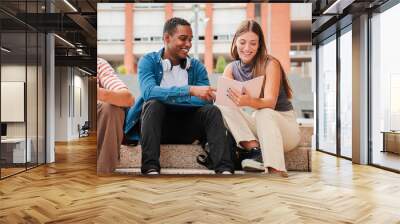 Two multiracial teenage studens learning together at university campus. African american schoolboy talking with a school girl about the homeworks. Young friends studying at highschool stairs. High Wall mural