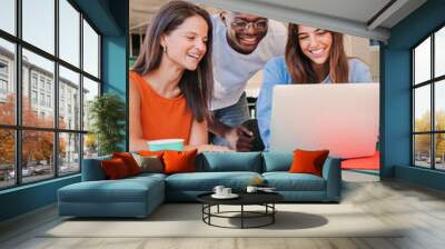 Vertical portrait of a group of multiracial happy teenage students using laptop, working on university homework project in college library. Meeting of young people looking information on computer Wall mural