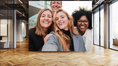 Vertical portrait. Group of real successful business woman smiling and having fun taking a selfie together. Teamwork of entrepreneur females looking at camera. Happy startup ladies laughing at work Wall mural