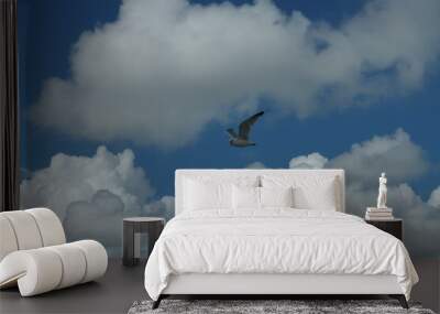 Flying seagull with a clear blue cloudy sky in the background. Wall mural