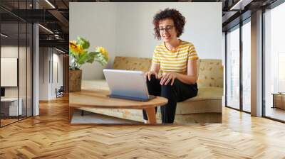 Woman sitting on sofa having a video call Wall mural