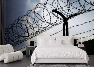 Dramatic clouds behind barbed wire fence on a prison wall Wall mural