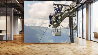 Two workers doing maintenance on cable car with Alps mountains in backgroun, Schonleitenbahn on Wildenkarkogel, Saalbach-Hinterglemm, Zell am See district, Salzburg federal state, Austria Wall mural