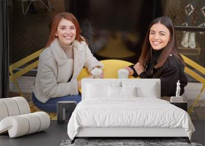 two beautiful model friends posing for the camera while holding a cup of coffee at a coffee shop Wall mural