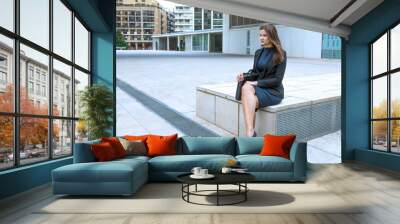 business woman sitting outside in office break time with elegant suit and briefcase Wall mural