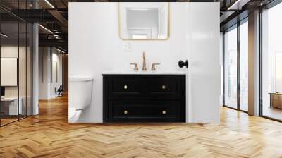 A bathroom with a black vanity, gold faucet and mirror, and a mosaic tiled floor. Wall mural