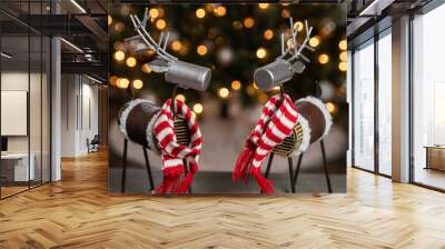 Homemade metal reindeer with a red and white striped scarf in front of a Christmas tree with white lights. Wall mural