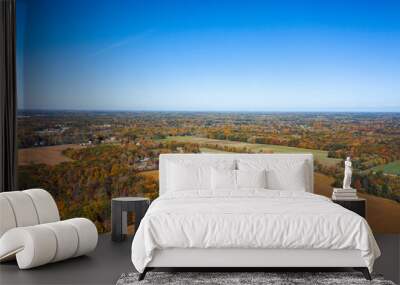 Beautiful autumn aerial view of patches of fall foliage covered trees in woods or forest surrounded by fields and farm land in rural Ohio. Wall mural