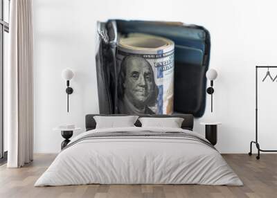 Close up of a black leather bi-fold wallet standing on edge with a wad of cash including hundred dollar bills rolled up between the open wallet with white background copy space. Wall mural