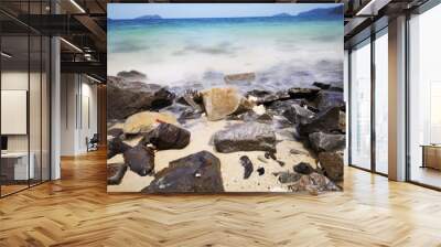 The beautiful silky smooth water waves and rocks on the sea shore during the sunny day. Wall mural