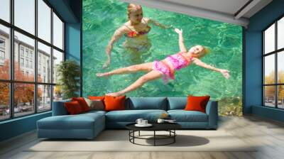 Young mother learn adorable daughter to relax in crystal clear l Wall mural