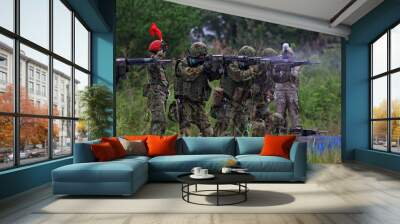 A group of soldiers are in a field, some of them are shooting guns Wall mural