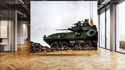 A military tank is driving through a muddy field Wall mural