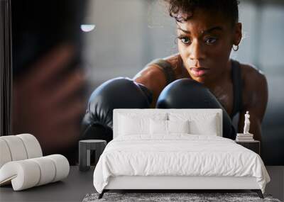 african woman boxing with punching bag in garage gym Wall mural