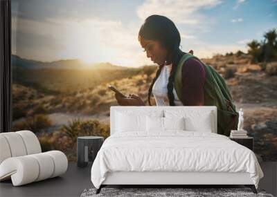 athletic african american woman with backpack looking at smart phone while hiking in red rock canyon Wall mural