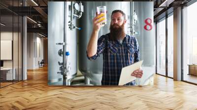 brewer checking beer for qaulity at brewery while holding clipboard Wall mural