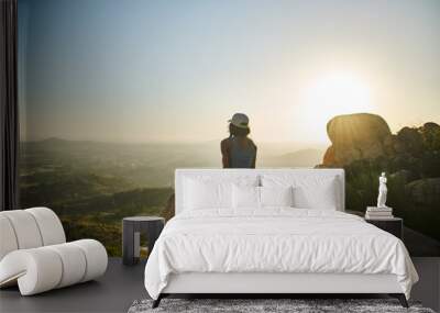 fit hiker at top of mountain sitting on huge rock watching sun set with san diego in the distance Wall mural