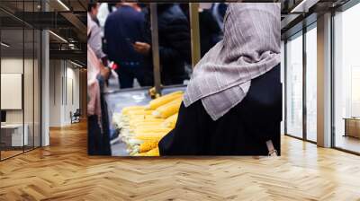 Anonymous muslim women with hijab buying corn on the cob at market stall on crowded street in Istanbul, Turkey Wall mural