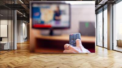 Closeup on tv remote control with hand of woman holding it. Changing television channels in living room. Schedule, choice variety concepts Wall mural