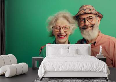 Happy smiling senior couple wearing sunglasses, green solid colorful background, image with space for text / coupl âgé souriant et heureus avec lunettes de soleil, fond vert, espace pour le texte Wall mural