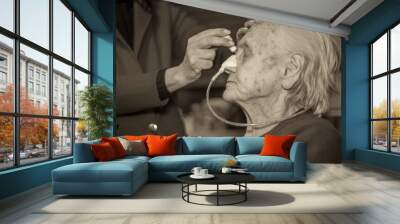 An elderly woman with a food cannula in her nose gets medication at home Wall mural